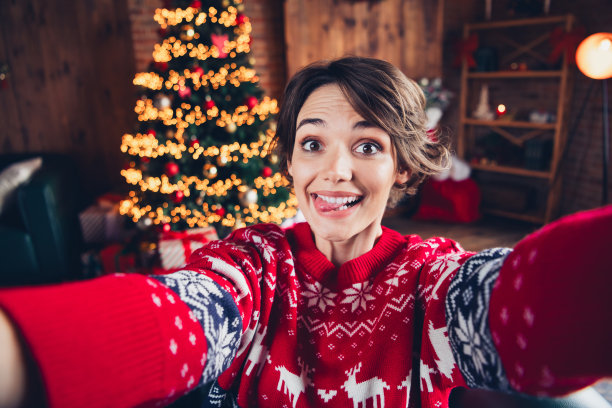 时髦的年轻女孩的自拍照片舌头伸出开玩笑，孩子气的玩耍，庆祝传统的气氛，圣诞气氛孤立在室内图片下载