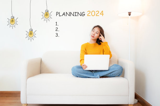 2024年和年轻女子一起计划新年快乐，在客厅沙发上用笔记本电脑。星星一起新年2024图片下载