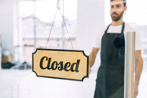 一位年轻英俊的男服务员走到透明的门前，把关着的牌子换成了开着的。图片下载