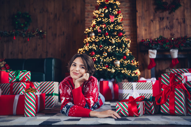 可爱的年轻女士躺在地板上享受早晨堆穿着时尚的红色毛衣圣诞树装饰室内客厅的照片图片下载