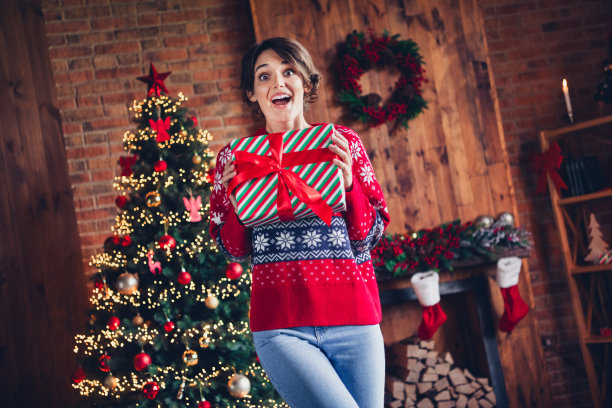 照片令人惊讶omg的反应年轻女子棕色波波头，穿着红色温暖的毛衣拿着包裹圣诞老人奇迹孤立的家庭背景图片下载