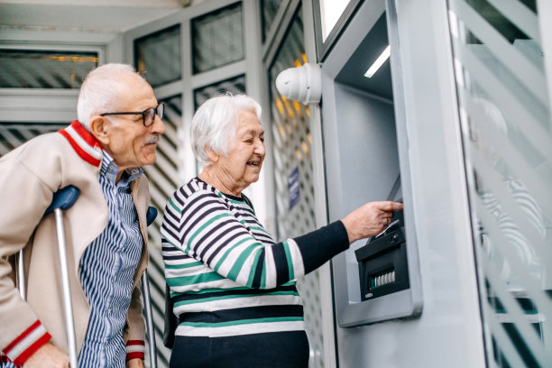 一对老夫妇在自动取款机前用信用卡取钱图片下载