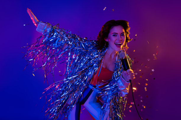 照片中迷人漂亮的女士穿着金箔夹克跳舞，享受着唱歌，孤立的霓虹紫色背景图片下载