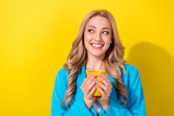 创意头脑开朗的女孩拿着新鲜的咖啡杯的照片，在黄色的背景上看起来空空荡荡的图片下载