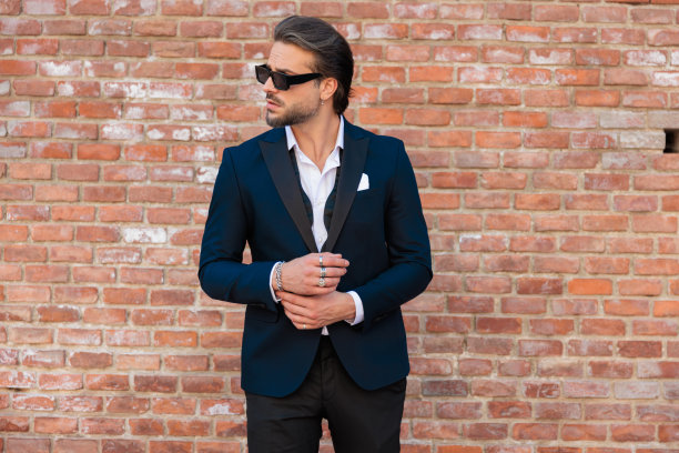 没刮胡子的优雅男人，穿着西装，戴着墨镜，看着旁边，抚摸着双手图片下载