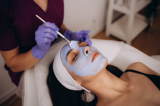 美容院美容师在女士脸上敷面膜。高质量照片图片下载