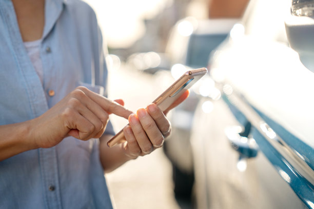 一名女子正在使用智能手机上的移动应用程序远程打开车门的特写照片。这项技术提供了一种方便、安全的进入车辆的方式，增强了用户的体验。图片下载
