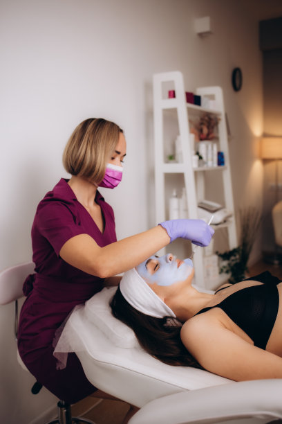 美容院美容师在女士脸上敷面膜。高质量照片图片下载