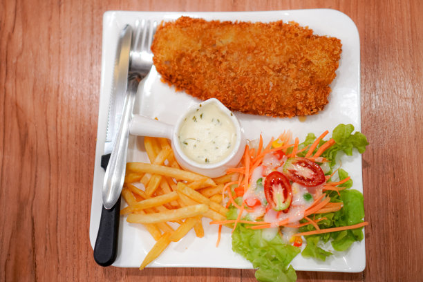 餐桌上盘子里的炸鸡、薯条和沙拉的俯视图照片。图片下载