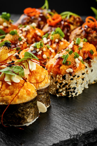 一套烤寿司卷在天妇罗与鲑鱼在黑色背景。日本料理，菜单图片图片下载