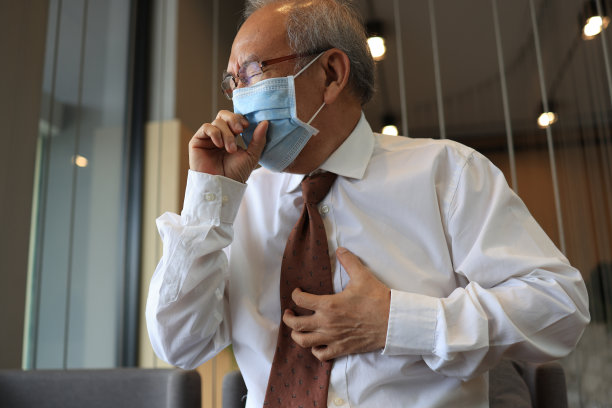 一位上了年纪的商人在办公室工作时戴着口罩咳嗽。在办公室工作和生病的生活方式图片下载