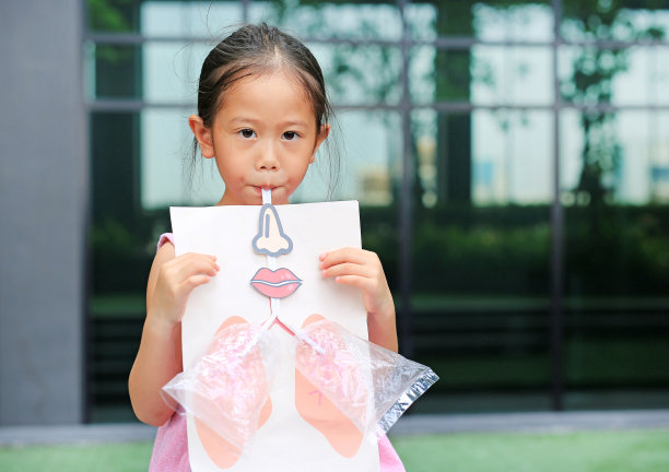 小女孩在玩吹口哨，模拟肺部的呼吸。医疗保健的概念。图片下载