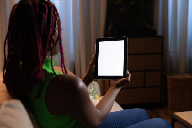非裔美国人，肤色深，注意力集中，手里拿着平板电脑，脸上看起来很专注。忙碌的专业人士，在家工作时用平板电脑与同事和客户保持联系图片下载