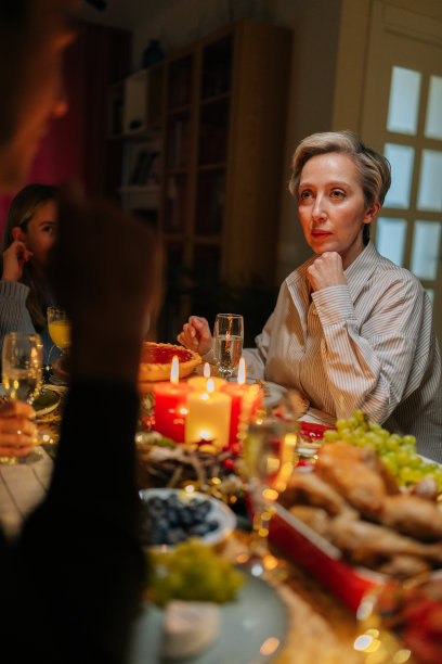 Vertica拍摄的一张照片中，一个无法辨认的年轻人拿着酒杯和香槟，在节日聚会的圣诞餐桌上和家人说祝酒词图片下载