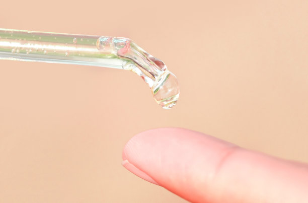 将面部精华胶原蛋白润肤霜滴入清澈的黄色瓶子中。护肤护理面部精华油，维生素c美容水疗概念图片下载