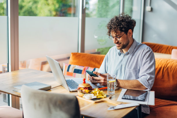 一位面带微笑的商人在餐厅的午餐休息时间使用手机图片下载