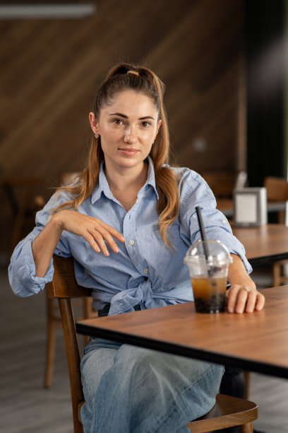 一个年轻女孩在餐馆里拿着一杯珍珠奶茶的照片图片下载