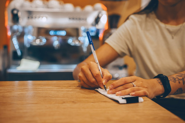 年轻的女服务员，咖啡师检查账单和收据，做笔记。咖啡馆老板做财务会计。图片下载