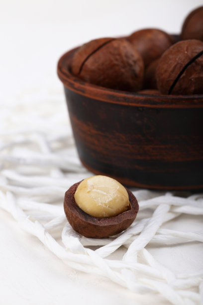 澳洲坚果在白色石头、石板或混凝土背景上的特写，超级食物和健康营养的概念，从上面或从上面看的照片，复古的色调图片下载