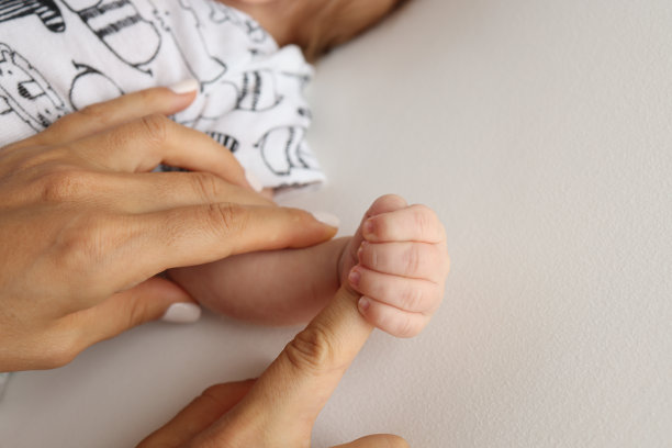 父母的手握着新生婴儿的手指。一对父母的手握着一个新生婴儿的拳头(特写)。家庭保健和医疗保健。白色背景的专业照片图片下载