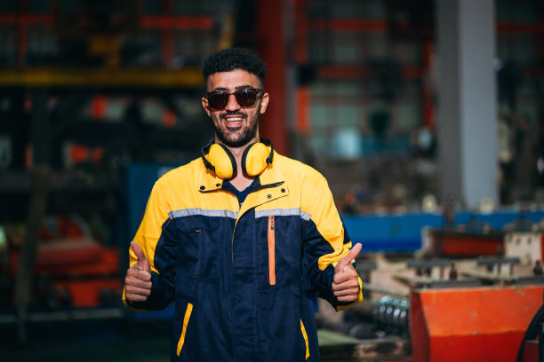 快乐的产业工人看着工厂机器的照片。工业钣金技术人员。图片下载