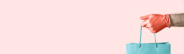 手戴红色橡胶手套，手里拿着蓝色纸袋。带复印空间的照片。大流行期间的安全概念。图片下载