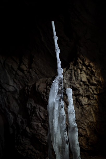 冰柱洞冷。冬天山洞里的石笋。冰冷的地牢王国。黑暗洞穴里的白光。地下一个大坑的入口。图片下载