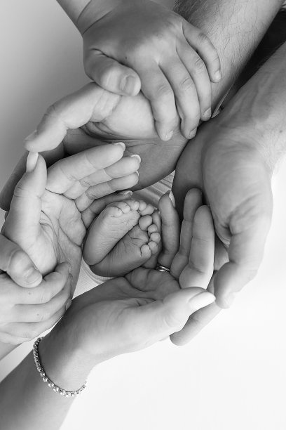 新生儿的腿，脚趾，脚和脚跟。用父母的手，爸爸，妈妈轻轻地抱着孩子的腿。微距摄影，特写。黑白照片。图片下载