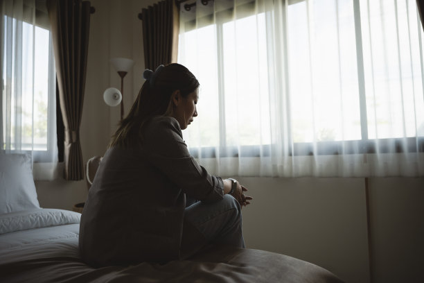 剪影沮丧的女人悲伤地坐在卧室的床上。悲伤的亚洲女性患有抑郁症失眠醒来，独自坐在床上在卧室。抑郁症健康人的概念。图片下载