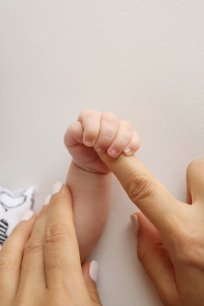 父母的手握着新生婴儿的手指。一对父母的手握着一个新生婴儿的拳头(特写)。家庭保健和医疗保健。白色背景的专业照片图片下载