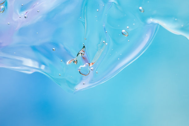 化妆品的凝胶质地。透明的奶油在蓝色的背景与气泡。宏观照片。模糊和选择性对焦。图片下载