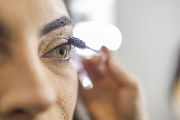 美容院的化妆师正在给一位年轻漂亮的女士涂睫毛膏图片下载