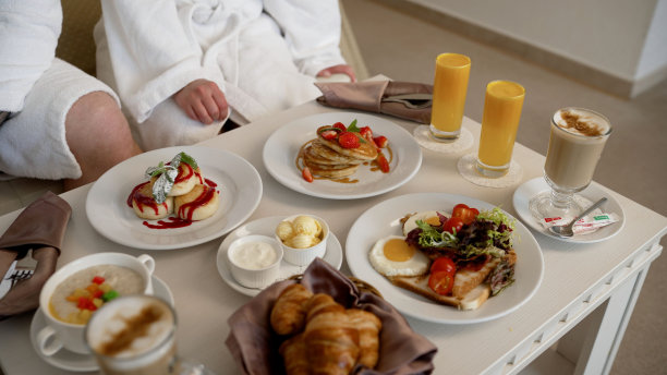 一个男孩和一个女孩在他们的酒店房间里吃早餐。早餐在酒店房间，在舒适的酒店。酒店的早餐送餐服务。美味的客房服务。豪华酒店的美味双人早餐。酒店房间的早餐。图片下载
