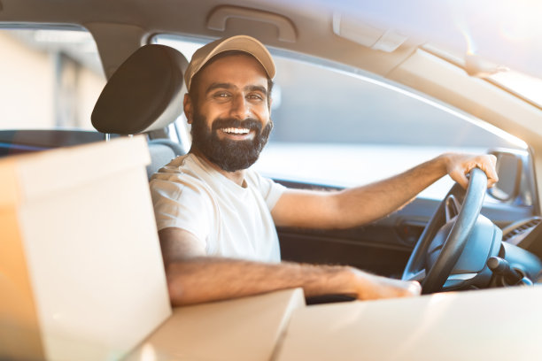 坐在装有包裹的汽车里的快乐的阿拉伯快递员图片下载
