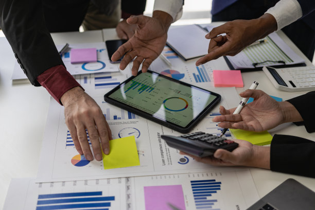 在商务演示或研讨会上，在会议室的桌子上处理文书工作的一组商务人员。该文件包含财务或营销数据、图形和图表，并配有笔记本电脑。特写照片图片下载