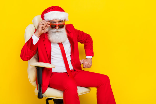 肖像优雅优雅的老人坐在椅子上，手触摸太阳镜看相机孤立的黄色背景图片下载