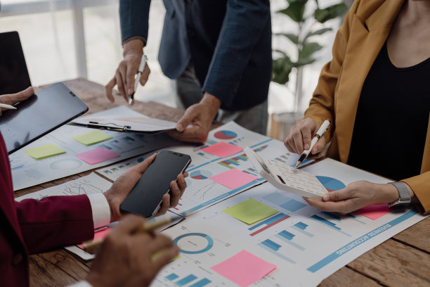 在商务演示或研讨会上，在会议室的桌子上处理文书工作的一组商务人员。该文件包含财务或营销数据、图形和图表，并配有笔记本电脑。特写照片图片下载