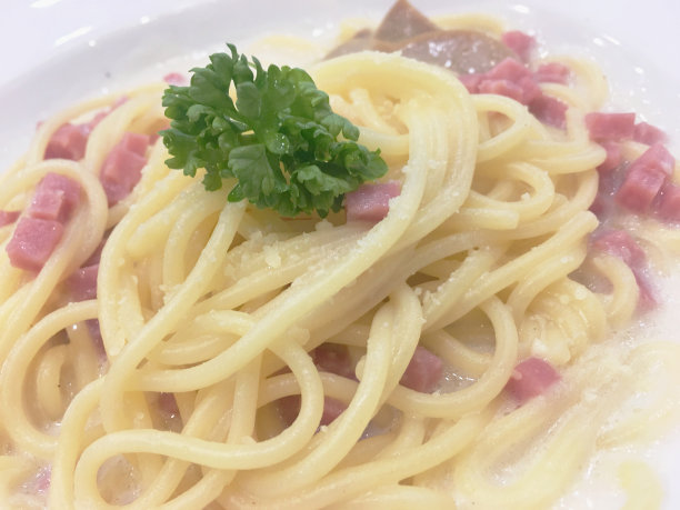 意大利面条，洋葱和蘑菇奶油酱，火腿和新鲜罗勒传统意大利菜风格的侧视图孤立的白色背景图片下载