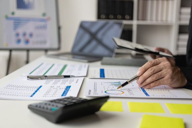 在商务演示或研讨会上，在会议室的桌子上处理文书工作的一组商务人员。该文件包含财务或营销数据、图形和图表，并配有笔记本电脑。特写照片图片下载