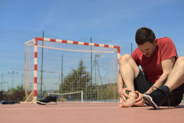 运动教练在感受他受伤的关节，脱下了鞋子。另一条腿在他前面。复制空间彩色图片。运动医学和物理治疗的概念图片下载