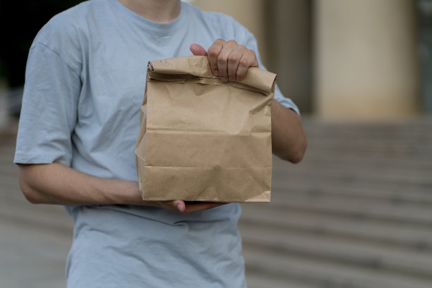 一名男子手持外卖纸袋，里面装着一些食物图片下载