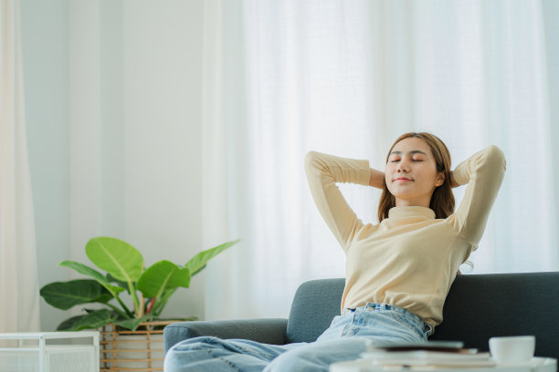 快乐、放松、随意的女人坐在椅子上，笔记本电脑放在她面前，双臂伸过头顶，生活方式、幸福和健康的概念。图片下载