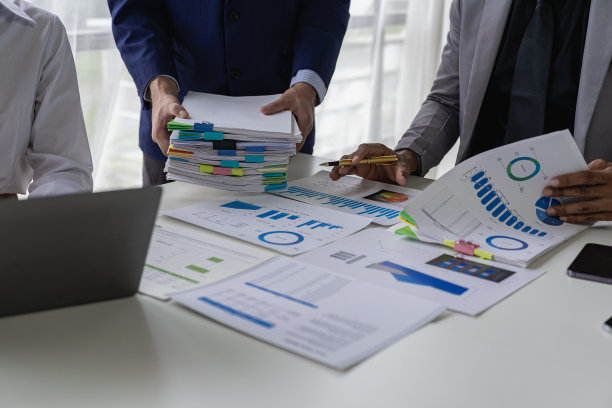 在商务演示或研讨会上，在会议室的桌子上处理文书工作的一组商务人员。该文件包含财务或营销数据、图形和图表，并配有笔记本电脑。特写照片图片下载