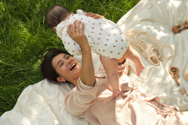 简单的生活乐趣:这张照片捕捉了一位年轻母亲和她的孩子在简单的草坪上兴高采烈的玩耍，让我们想起了生活中简单时刻的纯粹的幸福图片下载