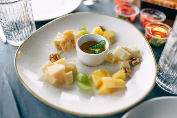 把不同种类的奶酪配上坚果和蜂蜜放在盘子里，美味的小吃图片下载