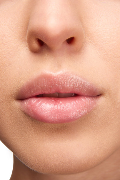 完美的自然唇妆。特写照片的女人嘴唇与光泽的口红。干燥嘴唇的润唇膏。图片下载