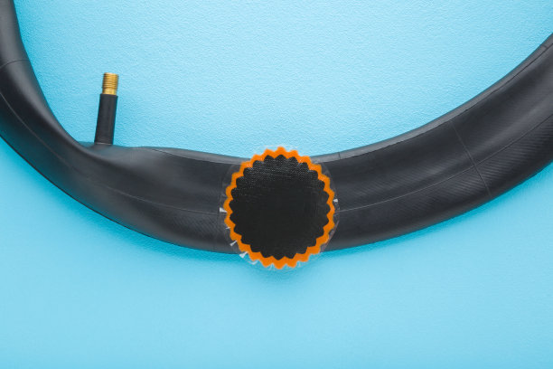 在浅蓝色桌面上，将补丁粘在黑色橡胶自行车内胎上。 钉子、螺丝或其他尖锐物体造成的孔洞修复。 淡色。 特写。 俯视。图片下载