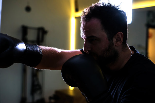 拳击手正在训练对着沙袋聚焦于前景的反向光水平照片图片下载