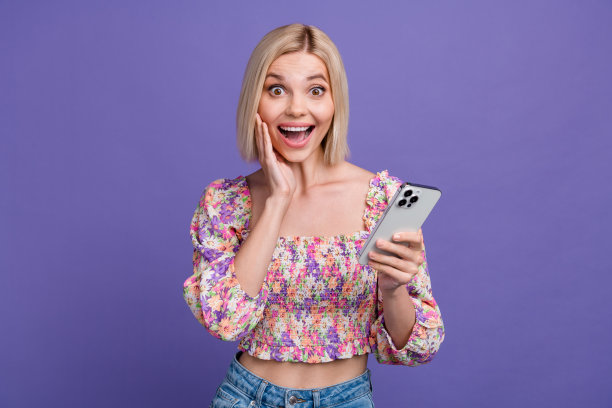 照片的甜美印象的女人穿着印花衬衫发短信苹果三星iphone设备孤立的紫色背景图片下载