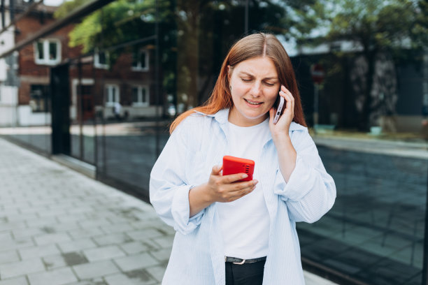 欢快的女士拿着电话的照片，受欢迎的博主正在写新文章和讲第二部手机。查看社交网络，发送短信或预订酒店图片下载